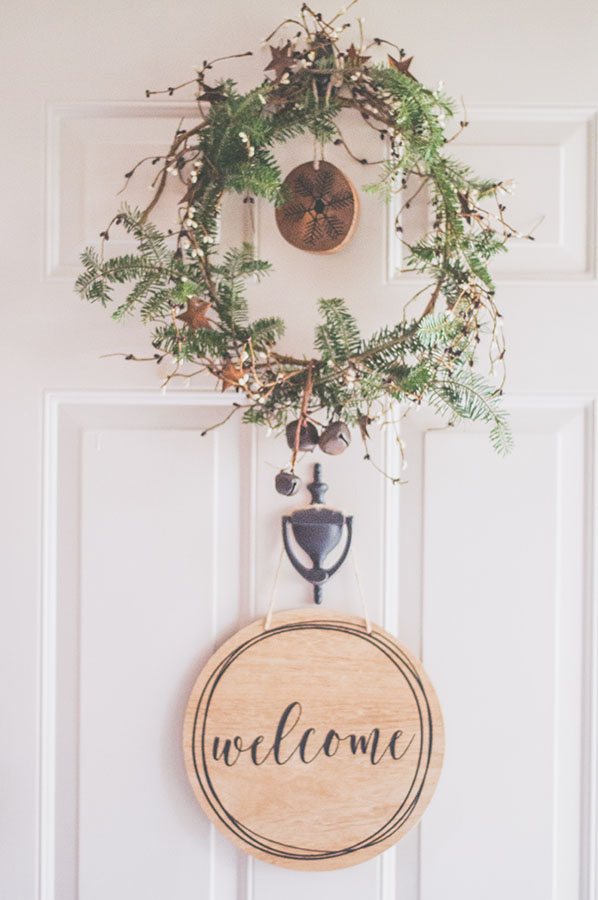 wooden welcome sign hanging on white door with wreath